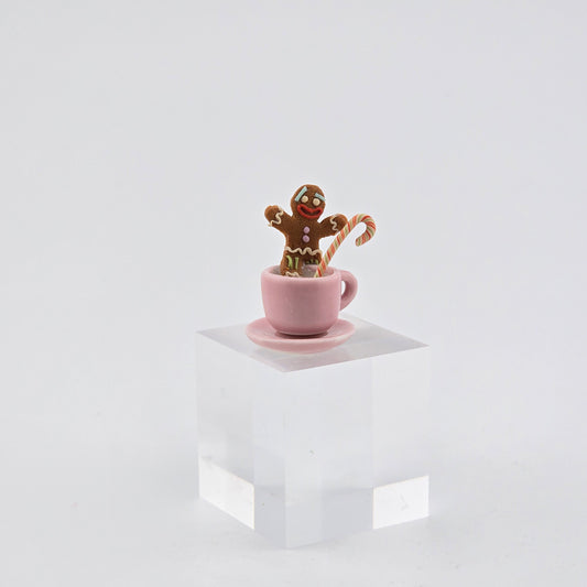 Gingerbread man in a pink cup with a candy cane on a white background