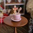 Load image into Gallery viewer, Pink teacup with gingerbread man and candy cane on a wooden table
