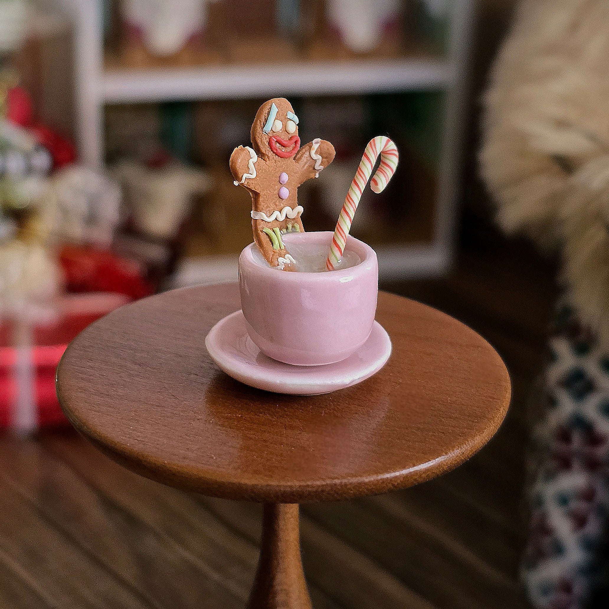 Pink teacup with gingerbread man and candy cane on a wooden table