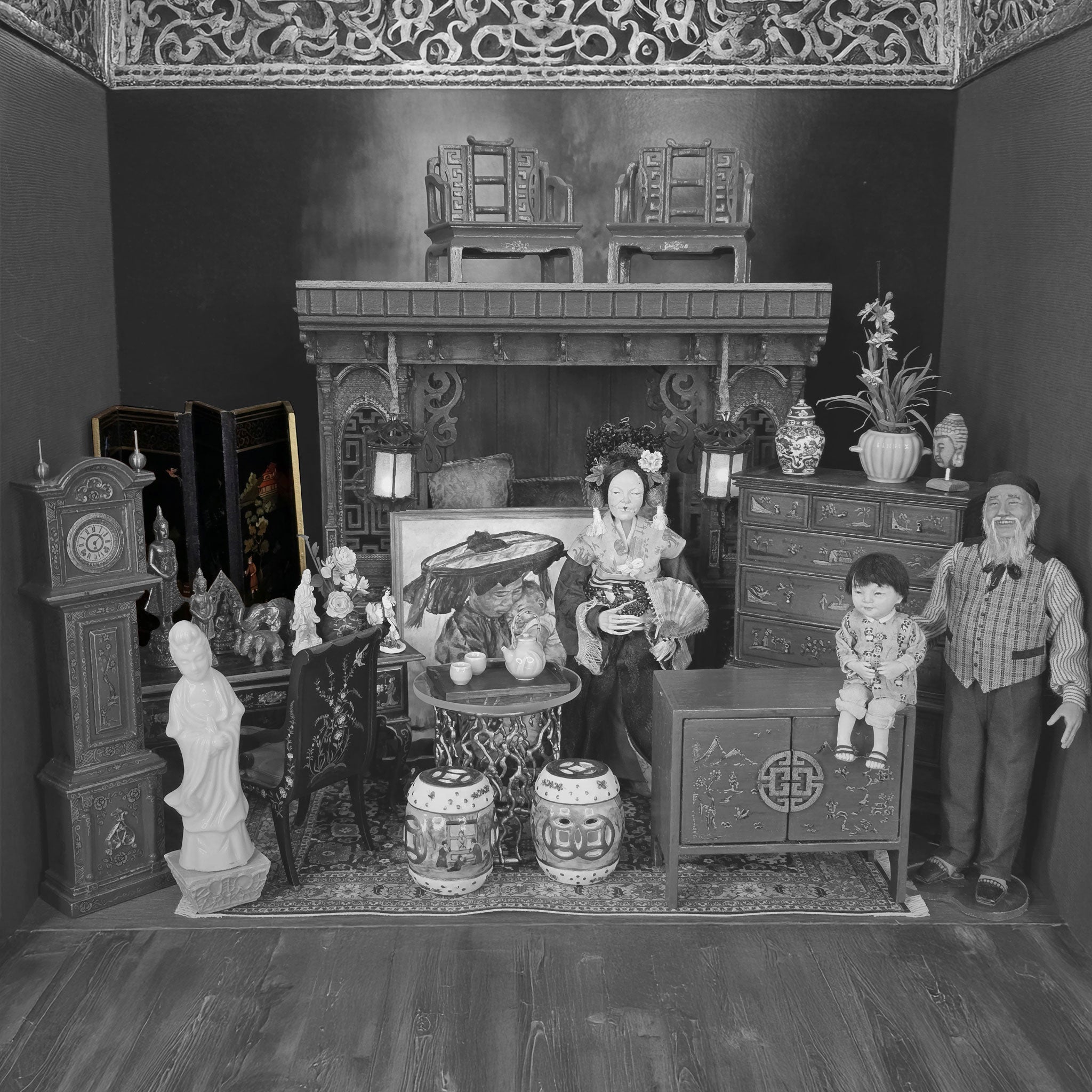 Black and white photo of a detailed dollhouse interior with furniture and decorative items.