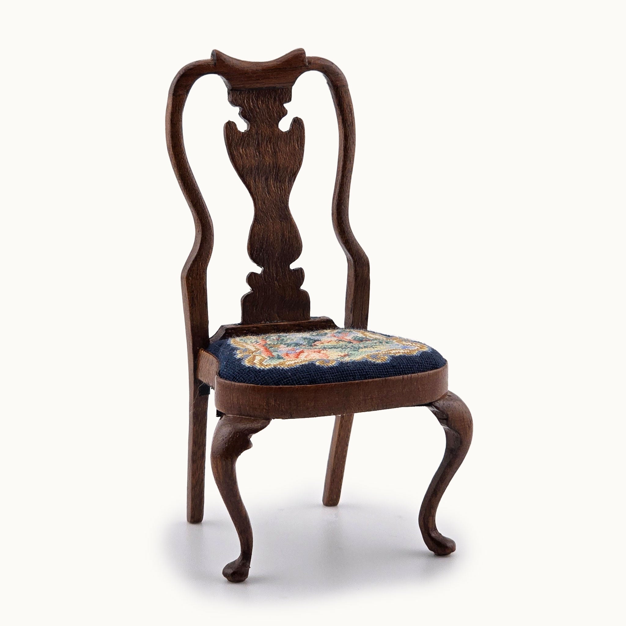 Wooden chair with floral petit point cushion on a white background