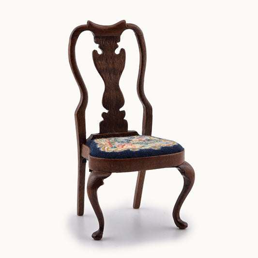 Wooden chair with floral petit point cushion on a white background