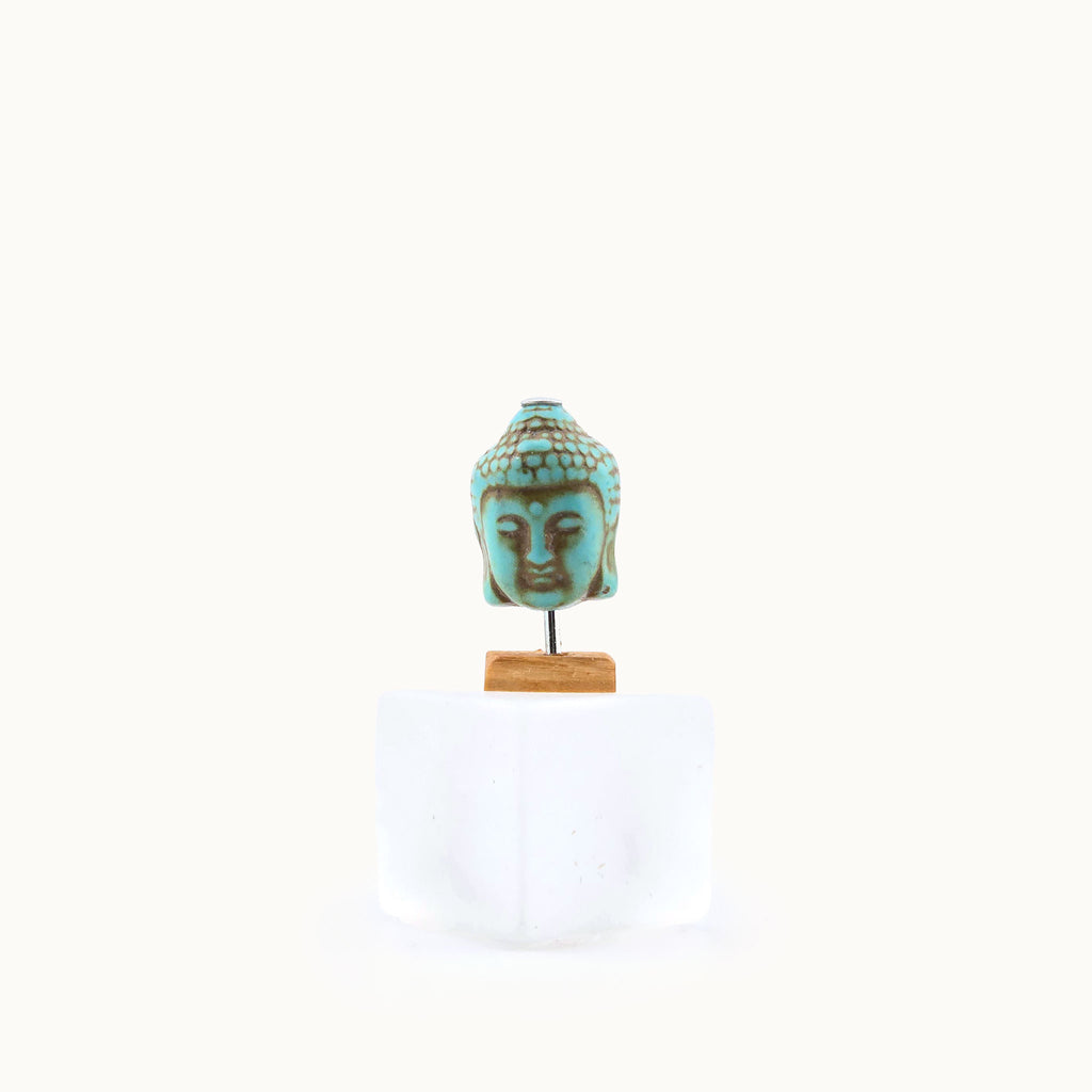 Miniature Turquoise Buddha head sculpture on a white background