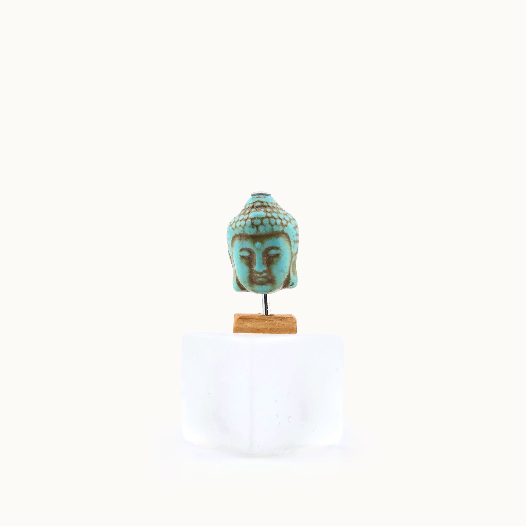 Miniature Turquoise Buddha head sculpture on a white background