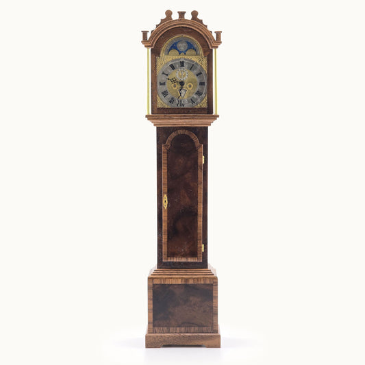 Wooden grandfather clock with detailed face on a white background