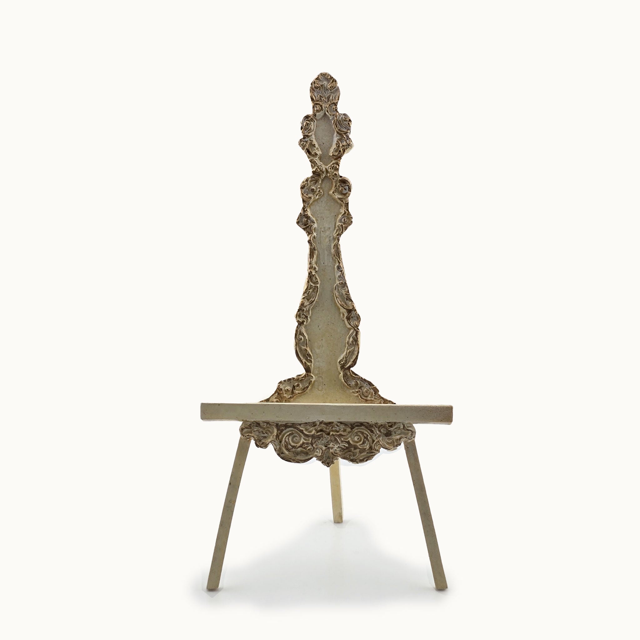 Decorative carved miniature easel with intricate back on a white background