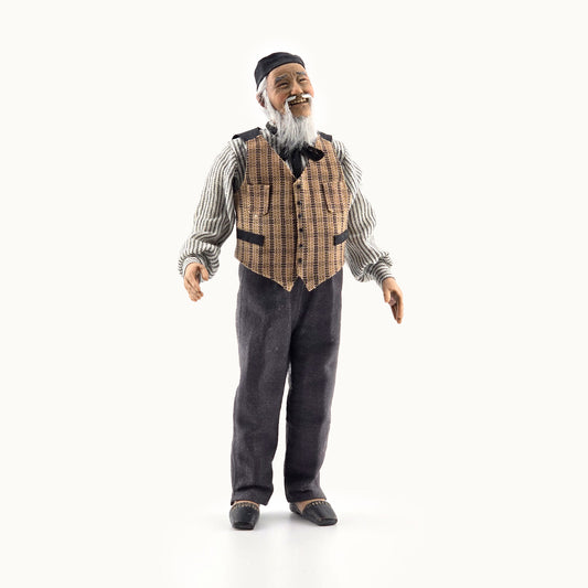 Vintage-style clay dollhouse doll, an elderly man with a checkered vest and bow tie on a white background
