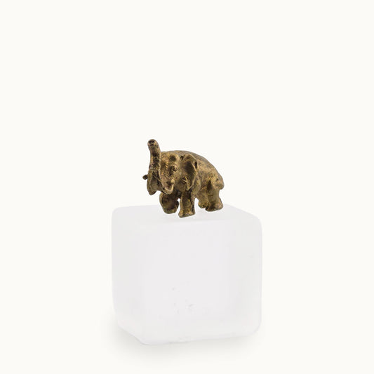 Bronze baby elephant figurine on a white pedestal against a white background