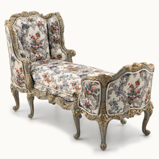 Decorative chaise chair with floral pattern and ornate carved frame on a white background