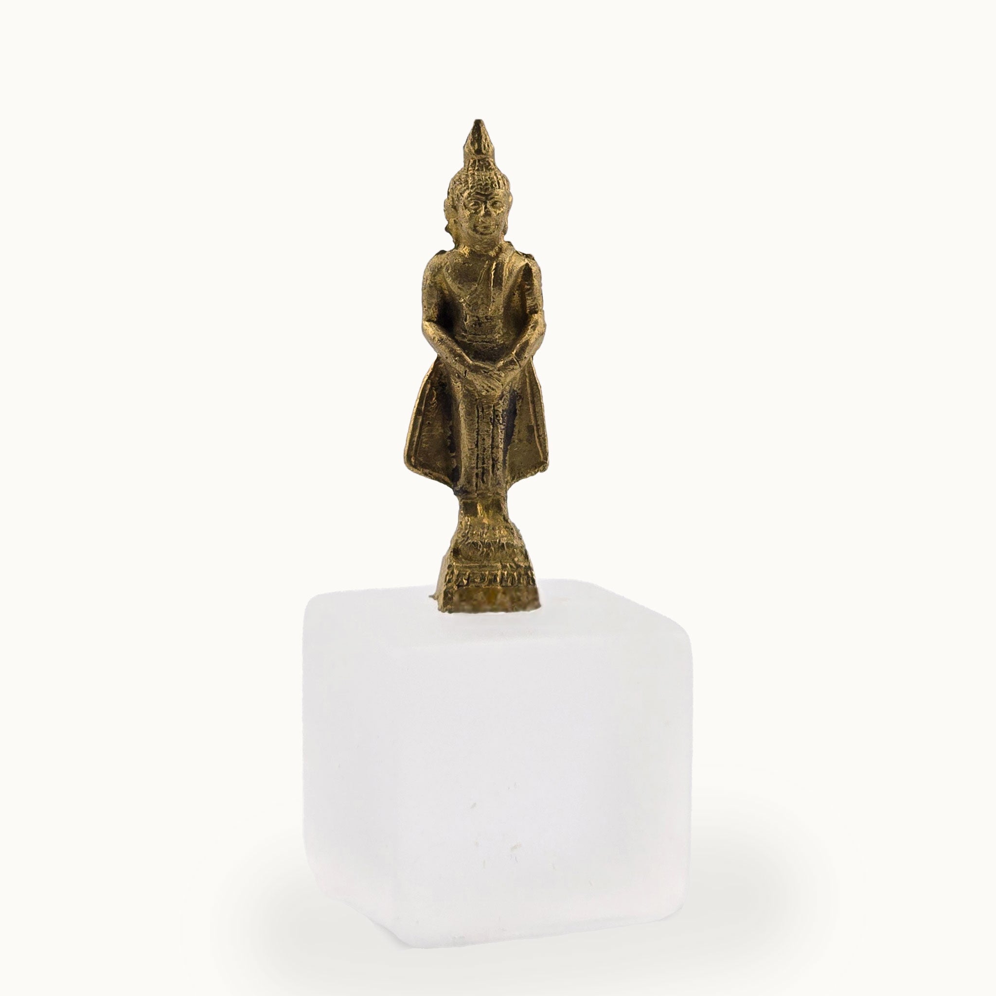 Bronze Buddha statue on a white pedestal against a white background