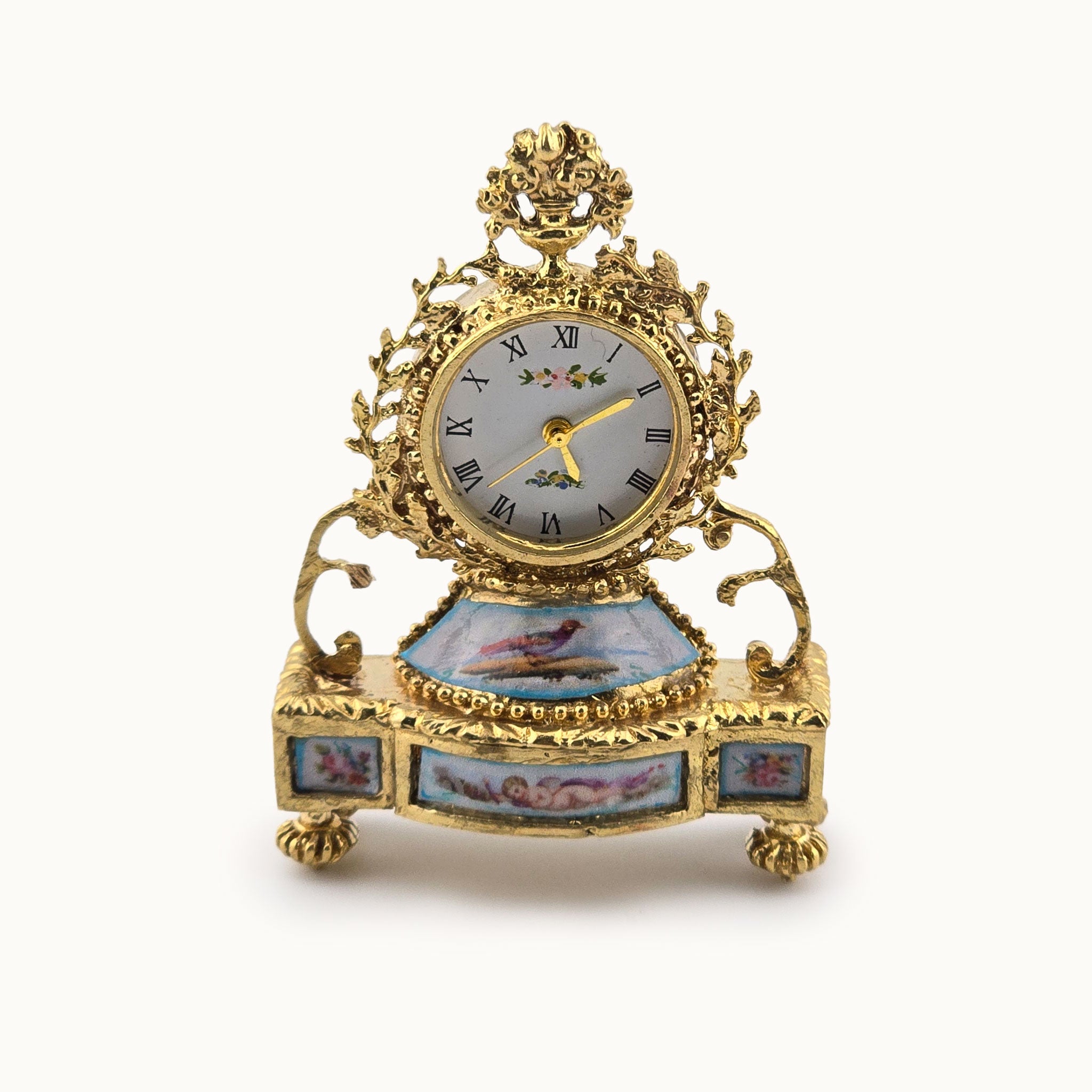 Decorative miniature dollhouse gold clock with intricate designs on a white background